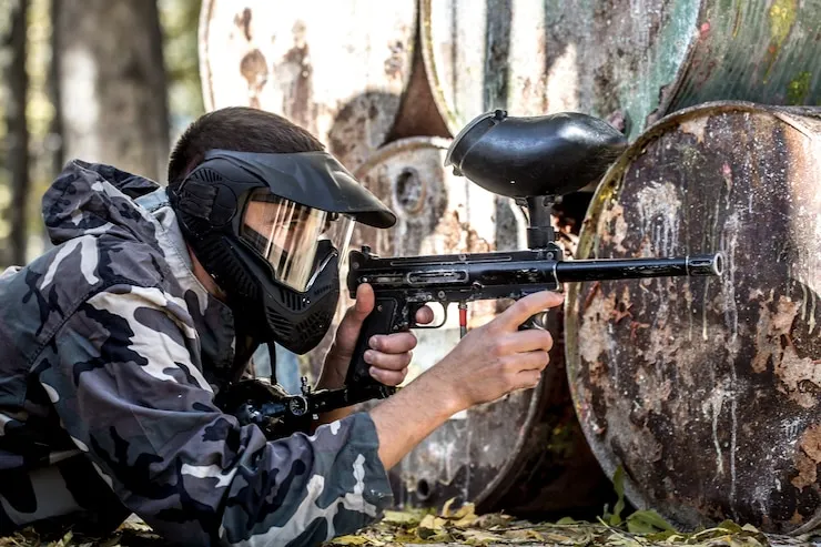 Jugador de paintball apuntando tras barricada en campo privado en las afueras de Medellín
