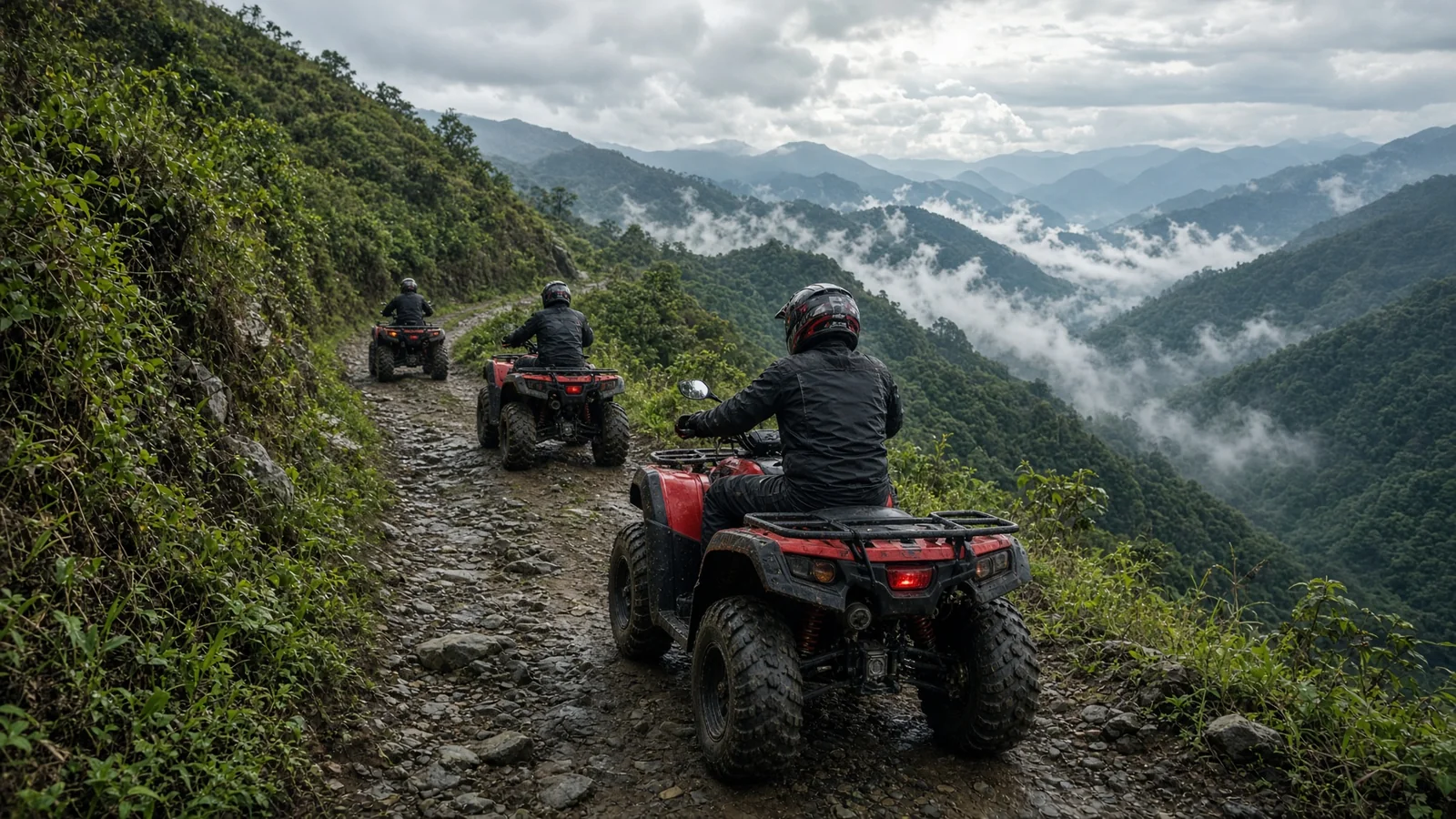 Tres pilotos en cuatrimotos rojos subiendo un sendero de montaña embarrado sobre los valles nublados de Medellín